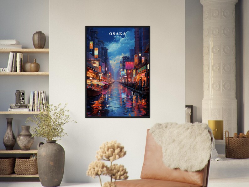 May include: A framed print of a painting depicting a nighttime scene in Osaka, Japan. The painting shows a canal with buildings and streetlights on either side. The water is reflecting the lights and there are people walking along the canal.