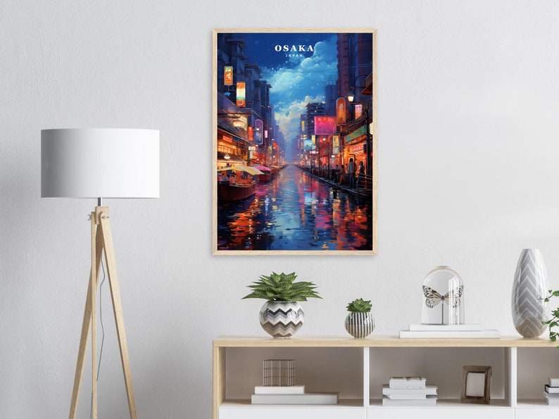 May include: A painting of a nighttime street scene in Osaka, Japan. The street is lined with buildings with colorful lights and signs. The street is wet from rain and reflects the lights. The painting is framed in wood.