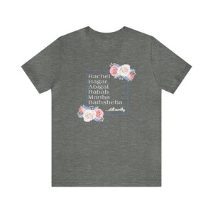 May include: A heather grey t-shirt with a floral design and the names Rachel, Hagar, Abigal, Rahab, Martha, and Bathsheba in a white box. The text "...still worthy" is below the names.