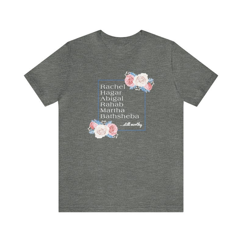May include: A heather grey t-shirt with a floral design and the names Rachel, Hagar, Abigal, Rahab, Martha, and Bathsheba in a white box. The text "...still worthy" is below the names.
