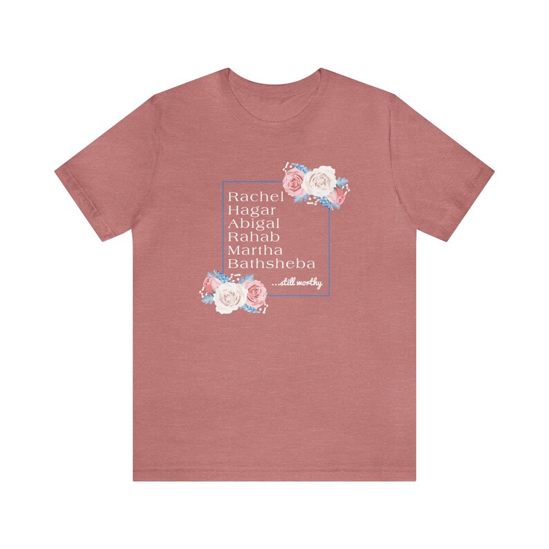 May include: A heather pink t-shirt with a floral design and a white box with the text "Rachel, Hagar, Abigal, Rahab, Martha, Bathsheba...still worthy".