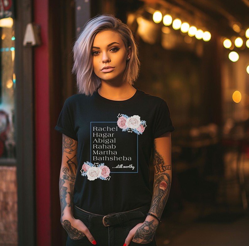 May include: Black t-shirt with a floral design and the text "Rachel Hagar Abigail Rahab Martha Bathsheba...still worthy" printed on the front.
