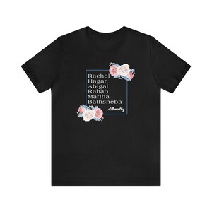 May include: Black t-shirt with a floral design and a blue box containing the text "Rachel, Hagar, Abigal, Rahab, Martha, Bathsheba...still worthy."