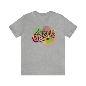 May include: Gray t-shirt with a colorful watercolor design of the word "JESUS" with a crown above it.