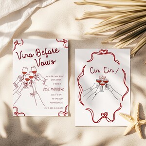 May include: Two white cards with red line art. One says "Vino Before Vows" with wine glasses and text. The other says "Cir Cir!" with wine glasses. The cards are on a sandy surface with a starfish and palm fronds.