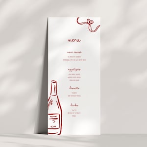 May include: A white menu card featuring red handwritten text and a red wine bottle illustration. The menu lists courses, appetizers, desserts, and drinks. A red ribbon design is at the top. The menu is for a restaurant or event.