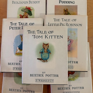 May include: A collection of six Beatrix Potter books with white covers, including The Tale of Benjamin Bunny, The Roly-Poly Pudding, The Tale of Peter Rabbit, The Tale of Little Pig Robinson, and The Tale of Tom Kitten, all published by F. Warne & Co.