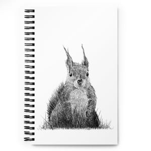 May include: A spiral-bound notebook with a monochrome illustration of a squirrel. The squirrel is drawn in detail, sitting in grass. The notebook has a clean, minimalist design, with a black spiral binding and a white background.