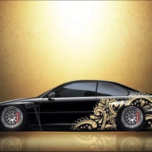 Könnte beinhalten: Ein schwarzes Auto mit goldenen Blumenaufklebern an der Seite. Das Auto ist ein Coupé mit einem eleganten Design.