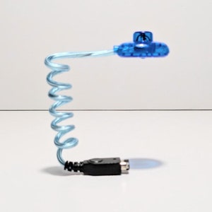 Può includere: Una luce LED USB blu e nera con un collo flessibile e a spirale. La luce ha la forma di un piccolo disco volante.