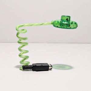 Può includere: Un adattatore per controller di videogiochi verde e nero con un cavo a spirale.