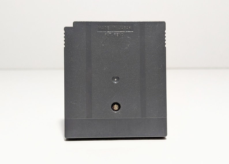 Op de afbeelding: Een zwarte Game Boy Color-spelcartridge met de tekst "MADE IN JAPAN" en "PAT. PEND." gedrukt op de achterkant.