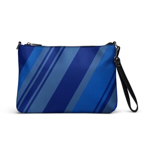 May include: A blue clutch bag featuring a diagonal stripe design in various shades of blue. It has a black zip closure and a black wrist strap. The bag is rectangular in shape.