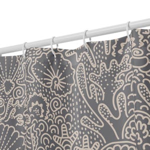 May include: A shower curtain featuring a dark grey background with a repeating light beige line art pattern of various seashells, coral, and starfish. The curtain is suspended from a white rod by white plastic rings, creating soft vertical folds.