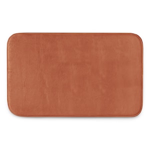 May include: A rectangular bath mat with rounded corners, featuring a solid, uniform terracotta orange color. The surface has a soft, plush texture with a consistent pile throughout, and the edges are finished with a matching fabric border.
