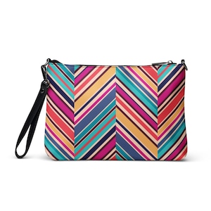 May include: A rectangular clutch bag with a black wrist strap. The bag has a colourful chevron pattern in shades of pink, red, blue, teal, and yellow. The zip is black.