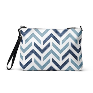 May include: A rectangular clutch bag with a black wrist strap and zip. The bag has a white background with a repeating chevron pattern in shades of blue. The zip and wrist strap are black.