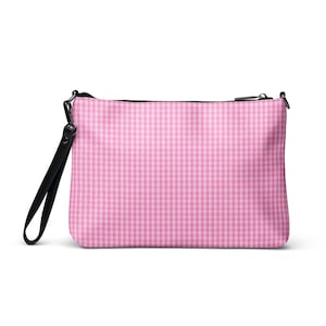 May include: A pink and white gingham pattern clutch bag with a black wrist strap and zip. The bag is rectangular and has a black zip closure. The wrist strap is made of black leather.