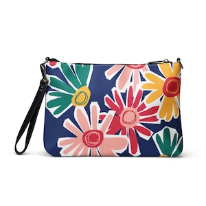 May include: A navy blue clutch bag adorned with a colourful floral print. The design showcases large, stylised flowers in pink, red, yellow, and green. It features a black wrist strap and a zip closure.
