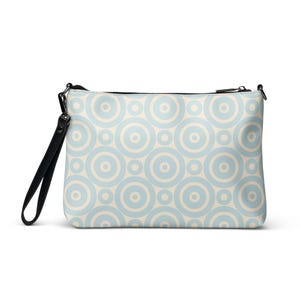 May include: A rectangular clutch bag featuring a pattern of light blue and cream-coloured concentric circles. It has a black zip and a black wrist strap. The bag is designed to be carried by hand.