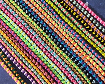 May include: A collection of colorful friendship bracelets made with braided string. The bracelets are arranged in a row, with the ends of the strings hanging down.
