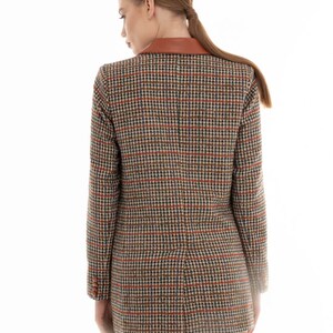 K&ouml;nnte beinhalten: Ein brauner und schwarzer karierter Blazer mit einem braunen Lederkragen. Der Blazer wird von einer Person mit langen braunen Haaren getragen.
