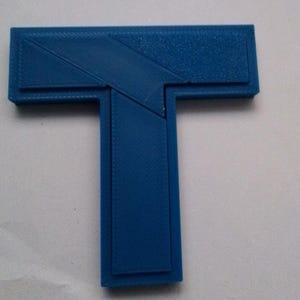 May include: A blue plastic puzzle shaped like the letter T. The puzzle is made up of several pieces that fit together.