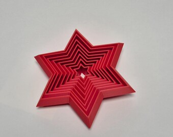 May include: A set of red star-shaped cookie cutters of varying sizes. The cutters are nested inside each other, creating a layered effect.