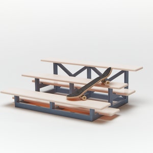 May include: A miniature wooden bleacher set with three tiers, painted in a light pink color, with a black skateboard resting on the top tier.