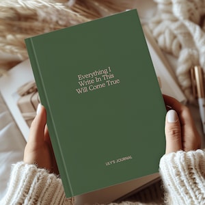 Könnte beinhalten: Ein grünes Journal mit dem Text "Everything I Write In This Will Come True" und "Lily's Journal" auf dem Einband.