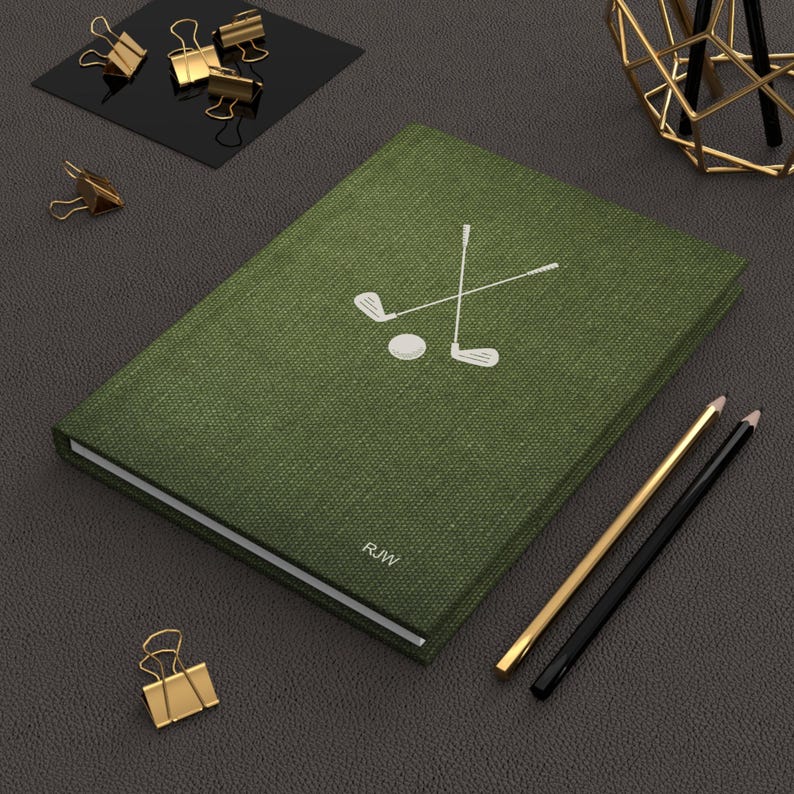 K&ouml;nnte beinhalten: Ein gr&uuml;nes, mit Leinen bezogenes Notizbuch mit einem wei&szlig;en Golfclub- und Ball-Design. Das Notizbuch tr&auml;gt die Initialen "R.W." auf dem Einband.