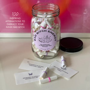 Bad Bitch Energy affirmations jar with the lid off and affirmation cards and scrolls in front of the jar.