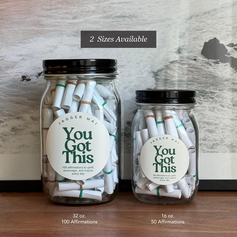 May include: Two glass jars with black lids filled with rolled-up white paper scrolls. The jars have labels that read "You Got This" and include the text "100 affirmations to uplift, encourage, and inspire every day." The larger jar is 32 oz and the smaller is 16 oz.