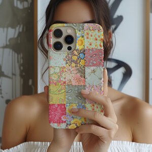 May include: A colorful patchwork phone case featuring a variety of floral and paisley patterns in shades of pink, yellow, green, and blue. The case has a rectangular shape with rounded corners and a camera cutout.