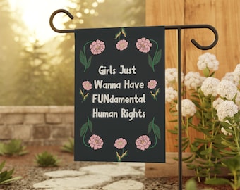 May include: A black garden flag with pink flowers and green leaves. The text on the flag reads "Girls Just Wanna Have FUNdamental Human Rights."