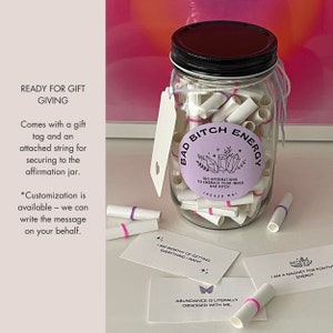 Affirmation jar with gift tag and string around it along with affirmation cards in front of it.