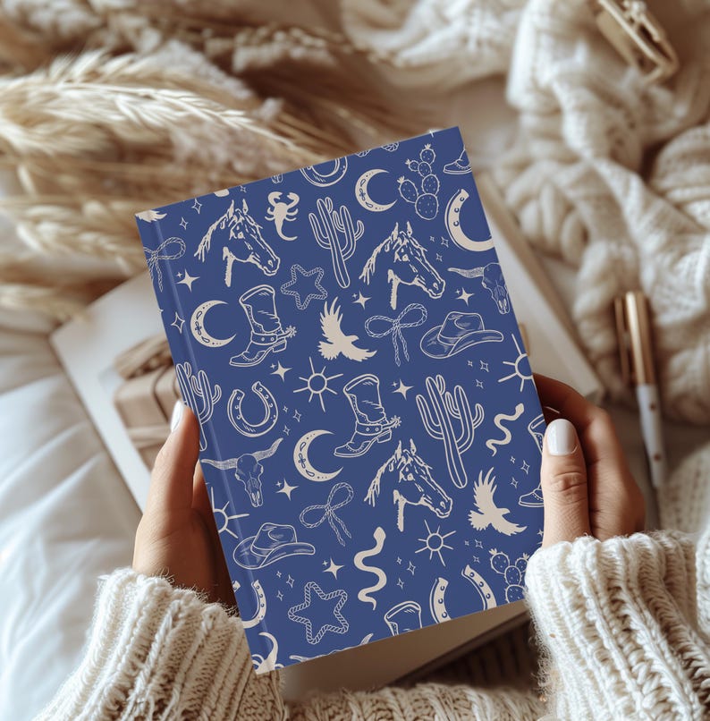 May include: A blue notebook with a white pattern of western-themed illustrations. The illustrations include horses, cacti, stars, boots, and horseshoes.