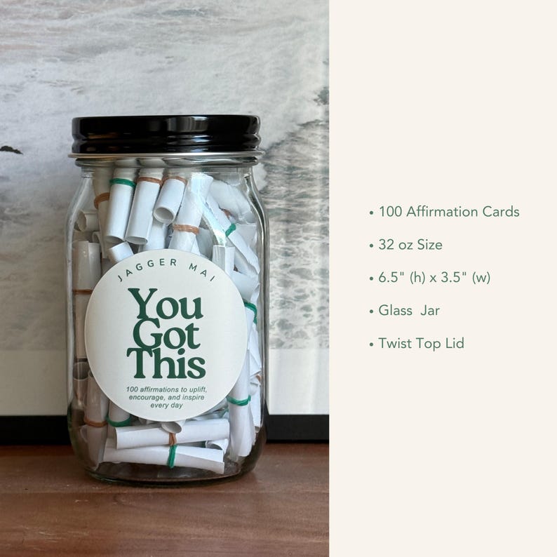 May include: A clear glass jar with a black twist-top lid filled with rolled-up affirmation cards. The jar has a white label with the text "You Got This" in green. The jar is 6.5 inches high and 3.5 inches wide.