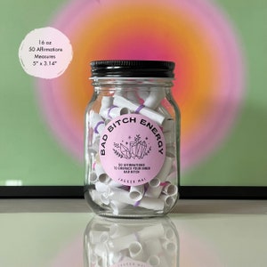 Smaller 16 oz Bad Bitch Energy affirmations jar in front of a green and pink poster print.