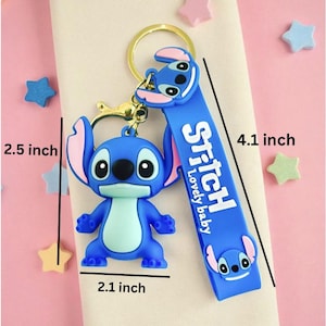 May include: A blue Stitch keychain with a gold-colored ring and clasp. The keychain features a 3D Stitch figure and a blue strap with the word "Stitch" and "Lovely baby" printed on it. The keychain is 4.1 inches long, 2.5 inches high, and 2.1 inches wide.