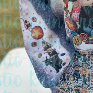 May include: A blue and white fabric with a whimsical design featuring a cat, a mouse, a star, and a balloon. The fabric has a distressed look with a faded background.