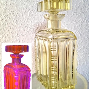 Puede incluir: Una decantador de vidrio amarillo con un tapón cuadrado y un diseño texturizado. El decantador está sentado en un pedestal blanco.