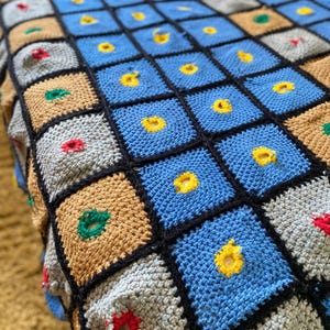 Peut inclure: Couverture crochetée à la main avec un motif patchwork. La couverture présente des carrés bleus, gris, beige et noirs, avec des accents jaunes, rouges et verts. La couverture est faite de fil doux et est idéale pour un lit ou un canapé.