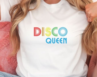 May include: A white t-shirt with the text "DISCO QUEEN" in rainbow colours. The letters are outlined in black and have a gradient effect.