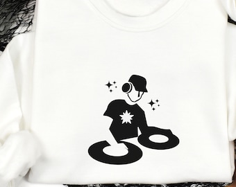 May include: White crewneck sweatshirt featuring a black graphic of a DJ with headphones, a hat, and turntables. The design includes a star on the DJ's shirt and sparkling star accents. The sweatshirt is a casual, comfortable garment.
