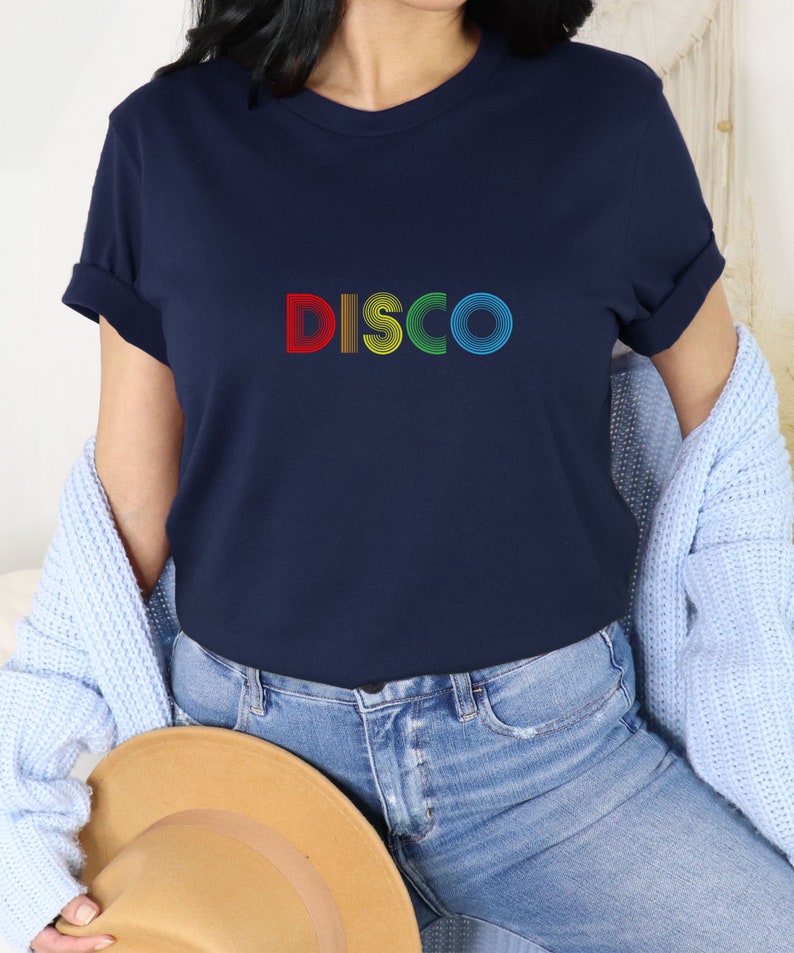 May include: A navy blue t-shirt with the word "DISCO" printed on the front in rainbow colors. The letters are made up of concentric circles.