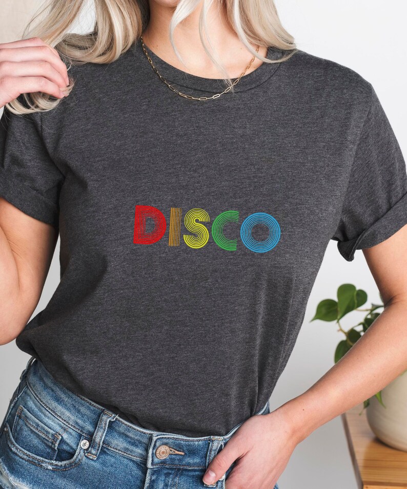 May include: A dark gray t-shirt with the word "DISCO" printed in rainbow colors. The letters are made up of concentric circles.