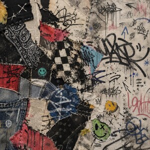 May include: A mixed-media textile collage featuring layered fabric patches including black paisley, checkered patterns, denim, and printed text. The surface is heavily decorated with black graffiti-style ink tags, arrows, and colorful smiley face icons.