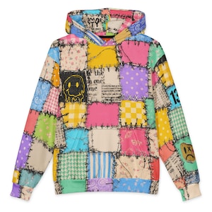 May include: A long-sleeve hooded sweatshirt featuring a colourful patchwork design. The pattern includes various squares with floral, polka dot, checkered, and houndstooth prints in yellow, pink, blue, and green, accented by black stitched details.
