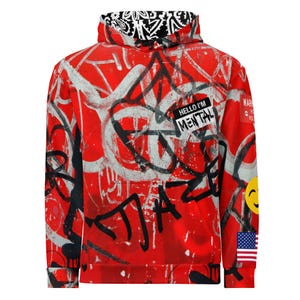 May include: Red hoodie with graffiti-style artwork in black and white. The design includes the text "HELLO I'M MENTAL" on a patch, a yellow smiley face, and an American flag. The hood lining features a black and white pattern.